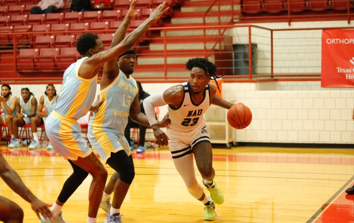 NAU basketball player Jalon Clark dribbles past opponents