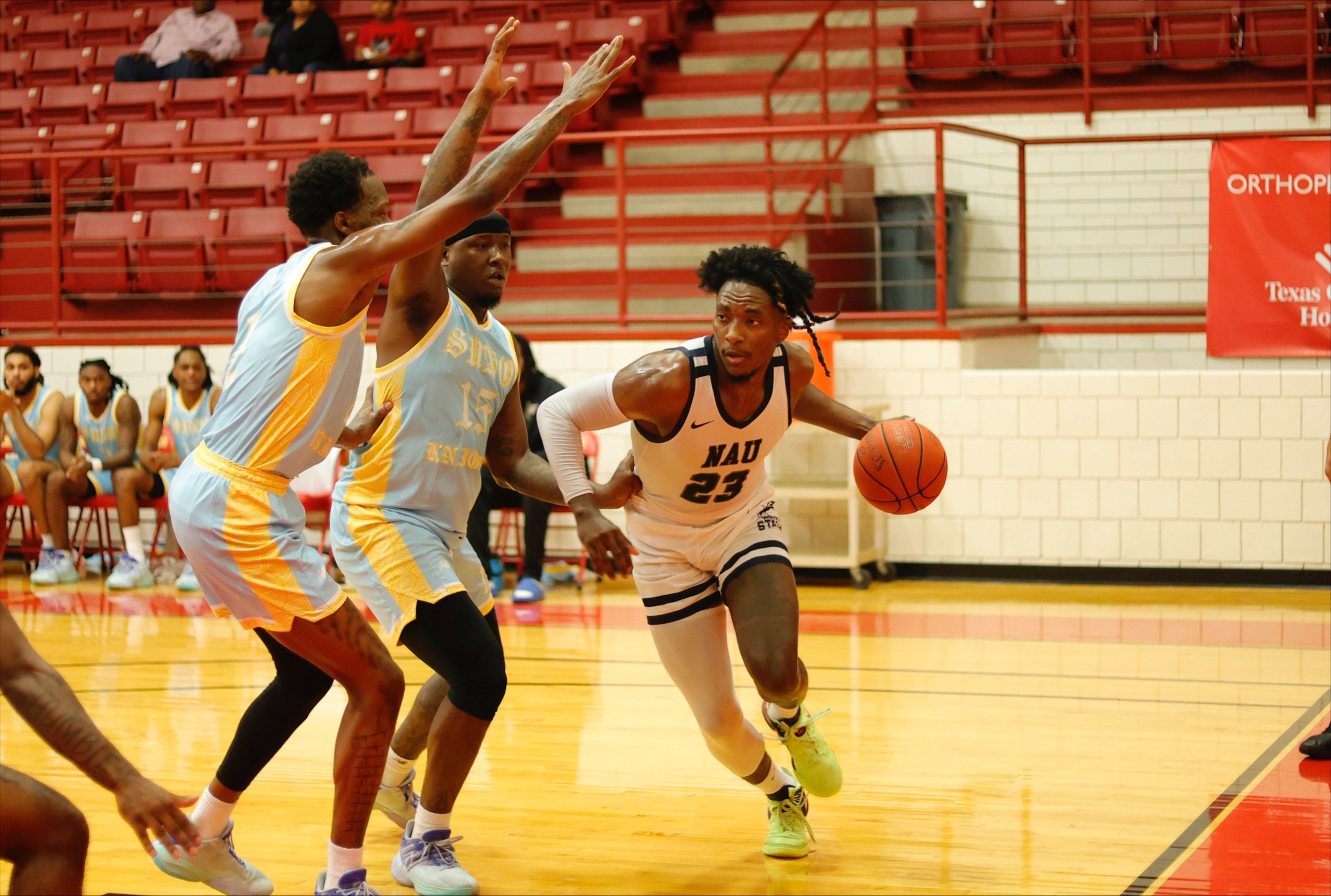 NAU basketball player Jalon Clark dribbles past opponents